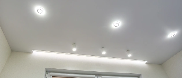 Wit spanplafond met lampen en kroonlijst.