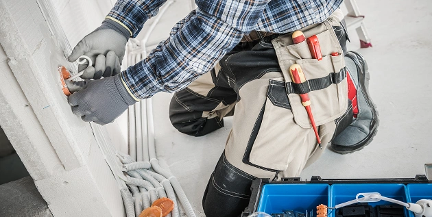 De elektricien legt de bedrading aan in een appartement dat wordt gerenoveerd.